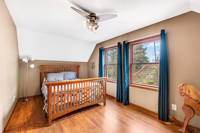 bedroom featuring hardwood / wood-style floors, vaulted ceiling, and ceiling fan