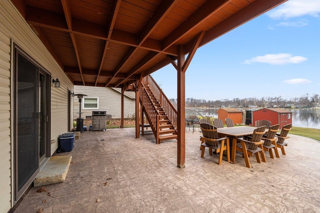 view of patio / terrace with a water view, grilling area, and a storage shed