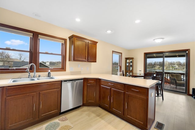 kitchen featuring dishwasher, kitchen peninsula, light hardwood / wood-style floors, and sink