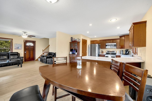 dining area featuring ceiling fan, light hardwood / wood-style flooring, a textured ceiling, and sink