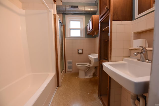 full bathroom with sink, heating unit, shower / bath combination, toilet, and tile walls