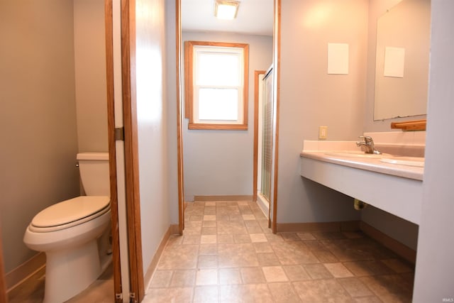 bathroom with toilet, a shower with shower door, and sink