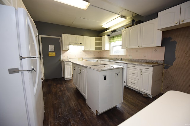 kitchen with white cabinets, white fridge, a kitchen island, and dark hardwood / wood-style floors