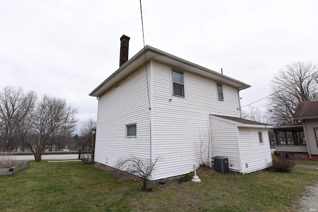 view of side of home featuring a lawn and central AC