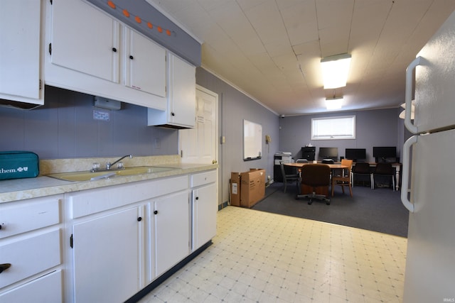 kitchen with white cabinets, sink, white fridge, and ornamental molding