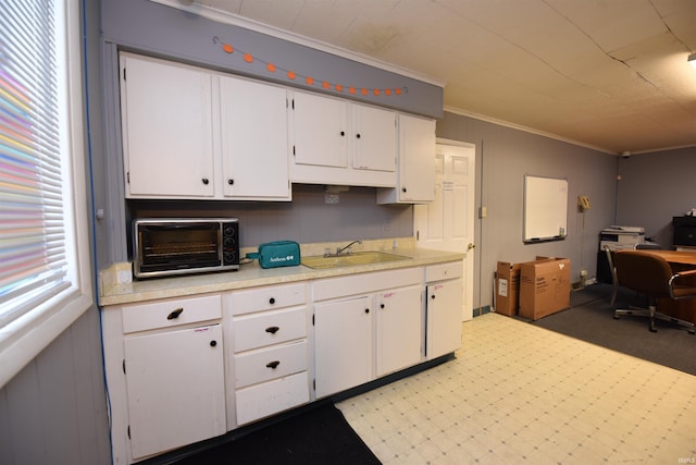 kitchen with light carpet, white cabinetry, ornamental molding, and sink