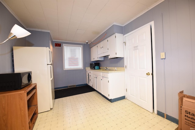 kitchen with white refrigerator, white cabinetry, and crown molding