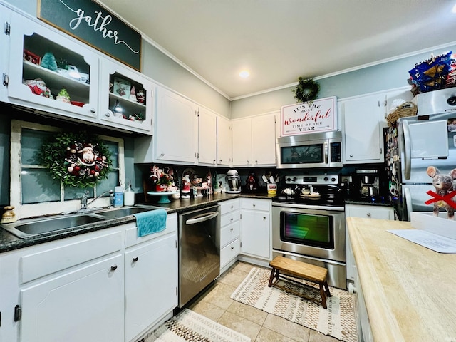 kitchen with crown molding, sink, appliances with stainless steel finishes, light tile patterned flooring, and white cabinetry