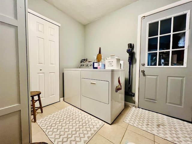 laundry room with washing machine and dryer, light tile patterned flooring, and a textured ceiling