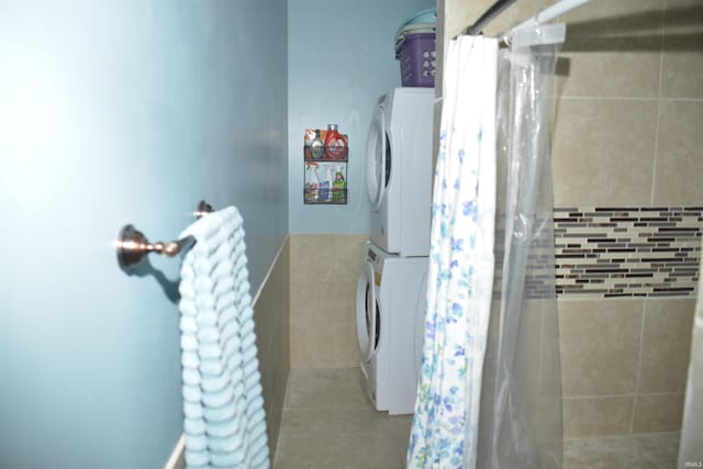 bathroom with stacked washer and dryer, curtained shower, and tile walls