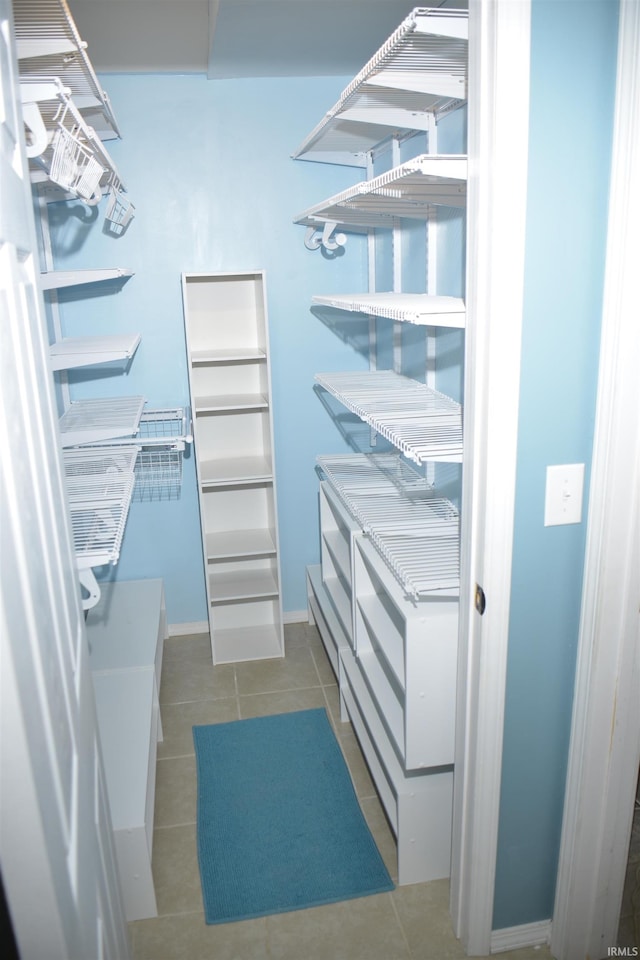 walk in closet with dark tile patterned flooring