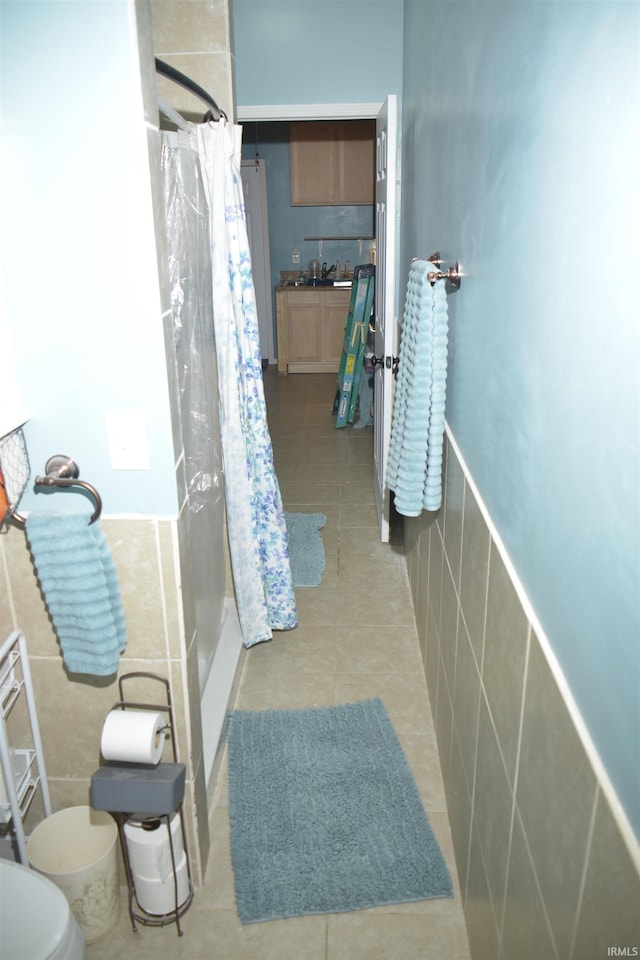 bathroom featuring tile patterned floors, sink, toilet, tile walls, and curtained shower