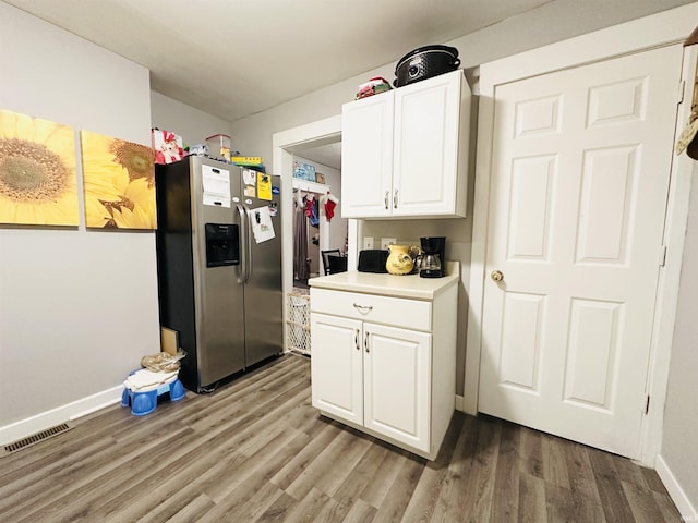 kitchen with stainless steel refrigerator with ice dispenser, white cabinetry, and hardwood / wood-style floors