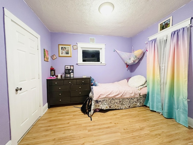 bedroom with light wood-type flooring and a textured ceiling