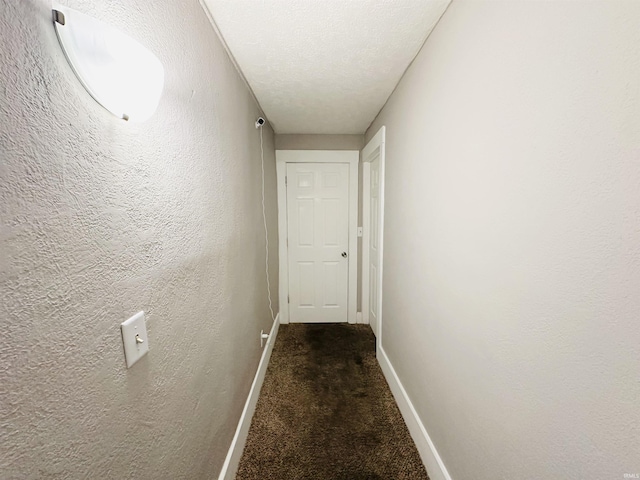 corridor with carpet floors and a textured ceiling