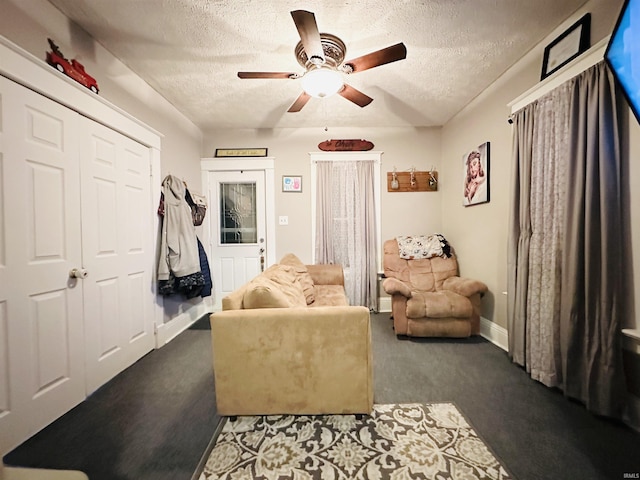 sitting room featuring ceiling fan, a textured ceiling, and dark colored carpet