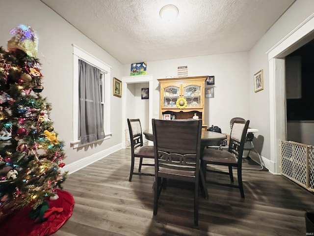 dining space featuring dark wood-type flooring and a textured ceiling