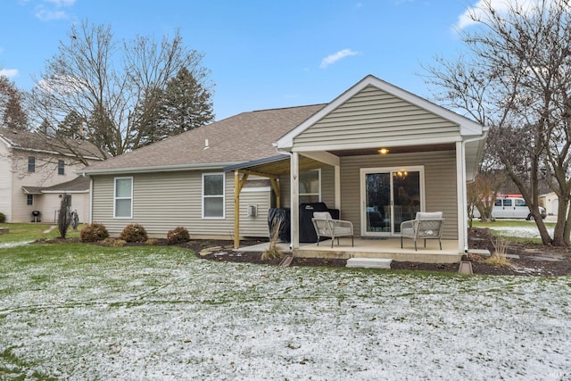 snow covered rear of property featuring a lawn