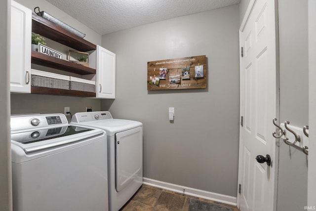 laundry area with washing machine and clothes dryer, cabinets, and a textured ceiling