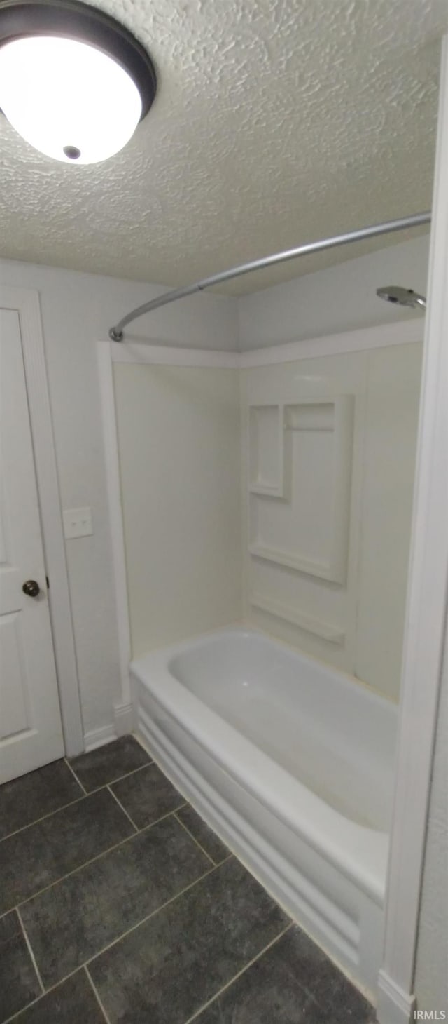 bathroom featuring tile patterned flooring, bathtub / shower combination, and a textured ceiling