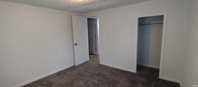 unfurnished bedroom with dark carpet, a textured ceiling, and a closet