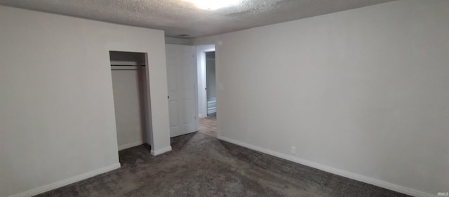 unfurnished bedroom featuring dark colored carpet, a textured ceiling, and a closet