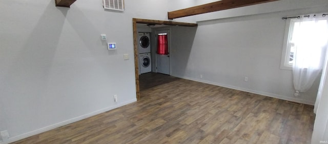 unfurnished room featuring beam ceiling, wood-type flooring, and stacked washer and clothes dryer