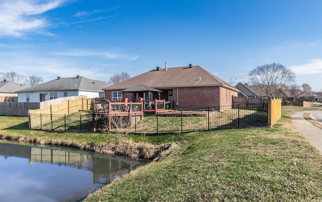 back of property with a deck with water view and a yard