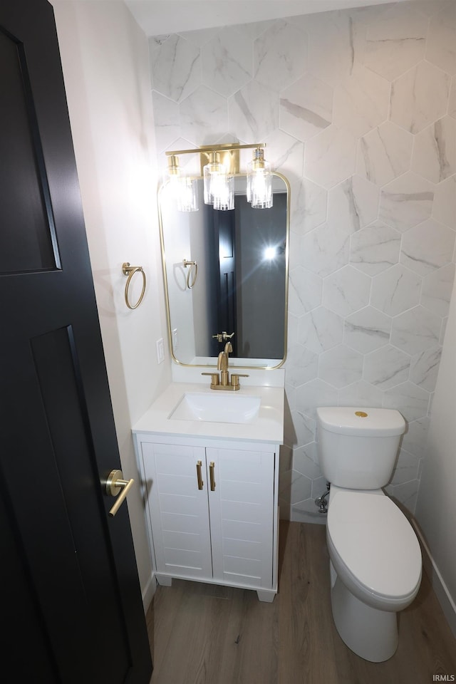 bathroom with vanity, toilet, wood-type flooring, and tile walls