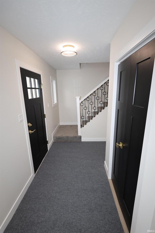 entrance foyer with dark colored carpet and a textured ceiling