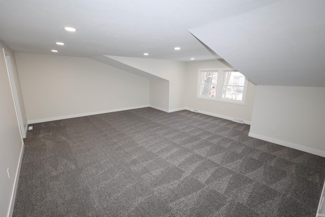 additional living space featuring dark colored carpet and vaulted ceiling