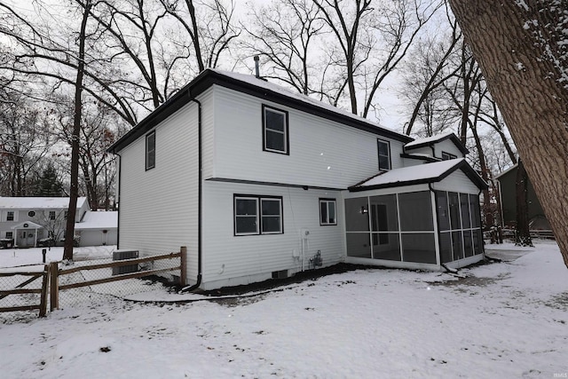 snow covered back of property with a sunroom and central AC