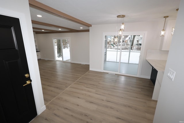 unfurnished dining area with beamed ceiling and hardwood / wood-style flooring