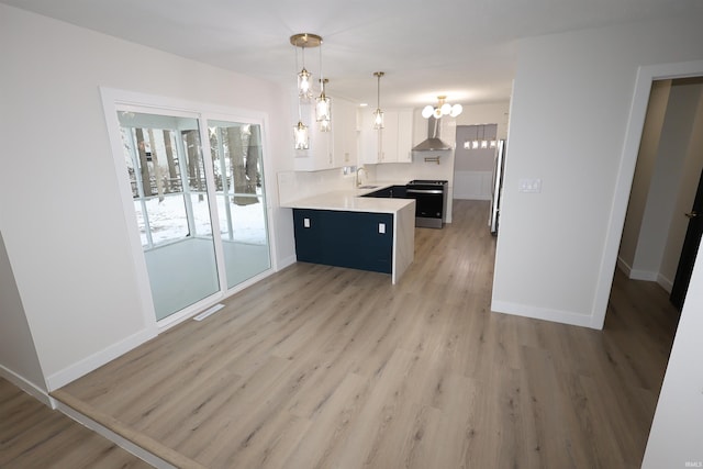 kitchen featuring stainless steel appliances, sink, wall chimney range hood, white cabinetry, and hanging light fixtures