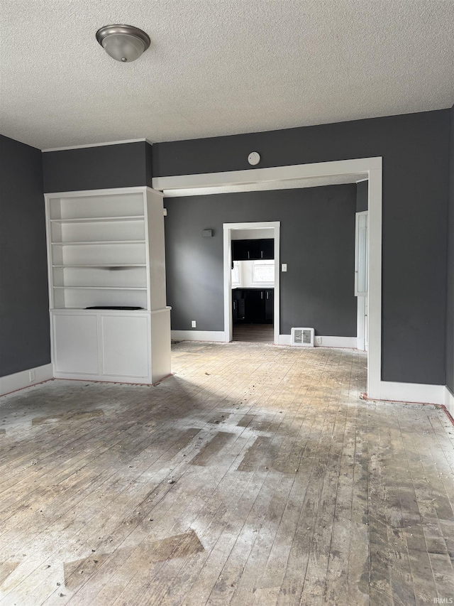 unfurnished living room with hardwood / wood-style floors and a textured ceiling