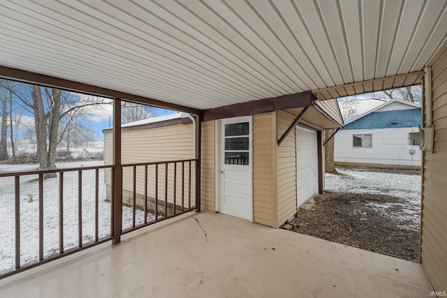 snow covered patio with an outbuilding and a garage