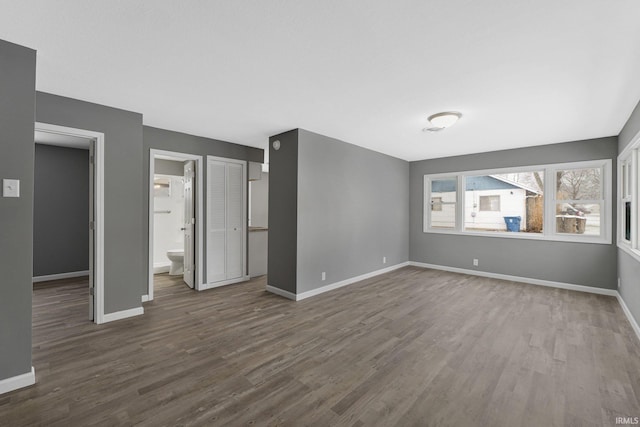 unfurnished bedroom featuring ensuite bathroom and dark hardwood / wood-style floors