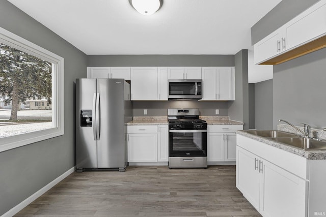 kitchen featuring white cabinets, appliances with stainless steel finishes, light hardwood / wood-style flooring, and sink