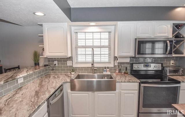 kitchen featuring white cabinetry, sink, stainless steel appliances, tasteful backsplash, and a textured ceiling