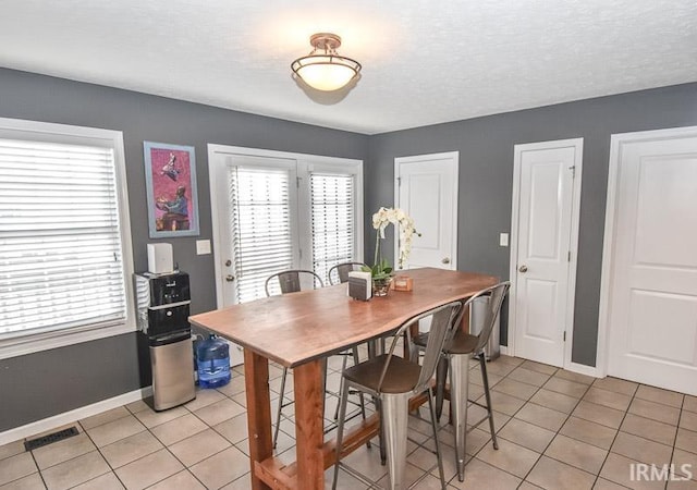 dining room with light tile patterned flooring, a healthy amount of sunlight, and a textured ceiling