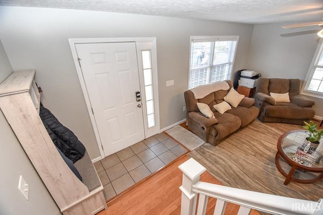 foyer featuring a textured ceiling, light wood-type flooring, plenty of natural light, and ceiling fan