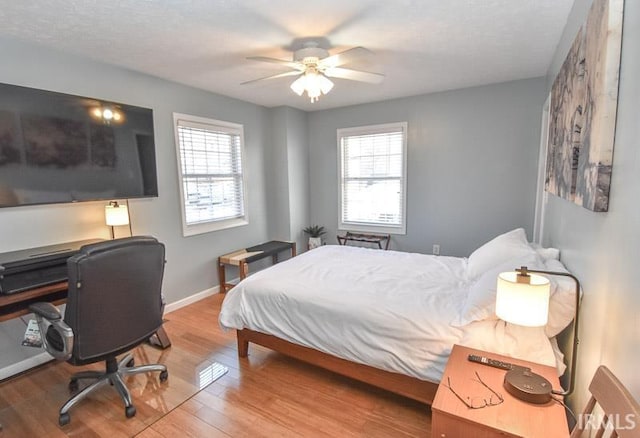 bedroom with multiple windows, ceiling fan, and wood-type flooring