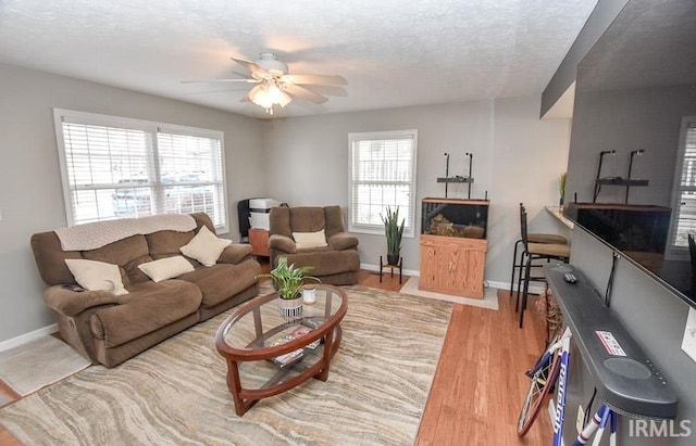 living room with hardwood / wood-style floors, ceiling fan, and a textured ceiling