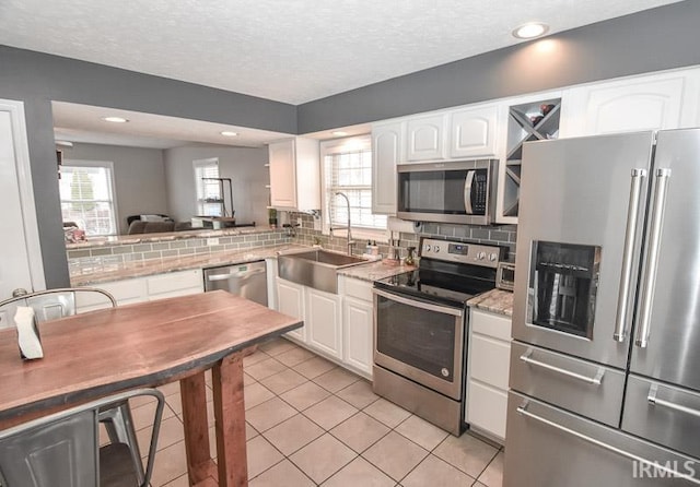 kitchen featuring appliances with stainless steel finishes, tasteful backsplash, white cabinetry, and sink