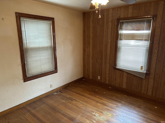 unfurnished room featuring wooden walls, ceiling fan, and dark wood-type flooring