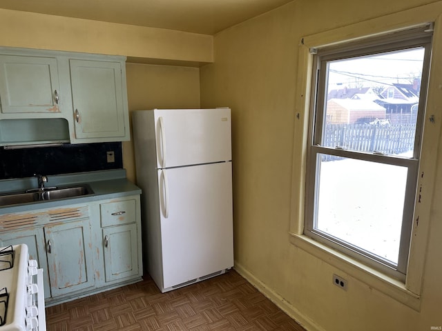 kitchen with white cabinets, white appliances, parquet floors, and sink