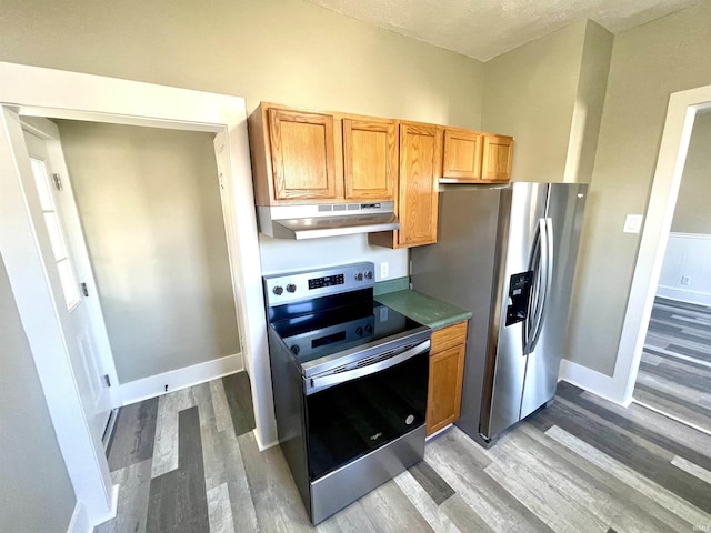 kitchen with wood-type flooring, a textured ceiling, and appliances with stainless steel finishes