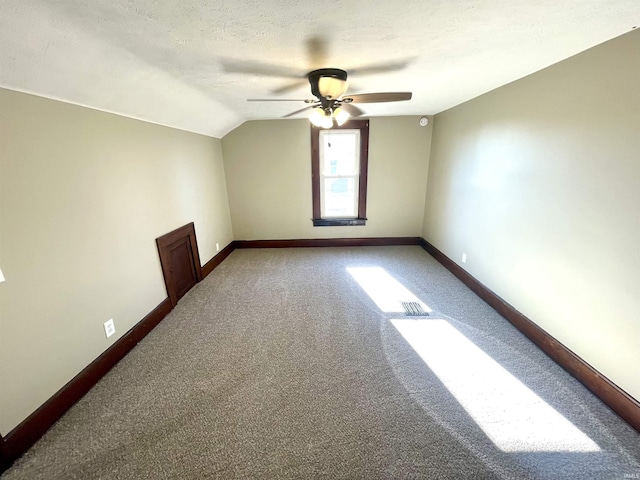 additional living space with a textured ceiling, ceiling fan, carpet flooring, and vaulted ceiling