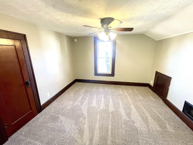 spare room featuring a textured ceiling, carpet floors, ceiling fan, and lofted ceiling