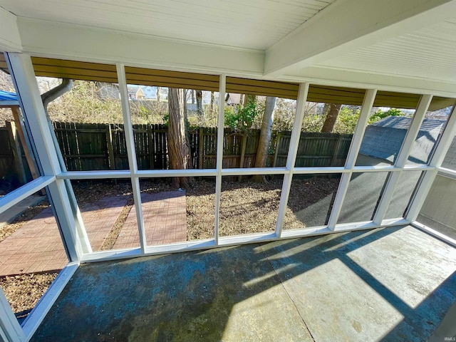 unfurnished sunroom featuring beam ceiling